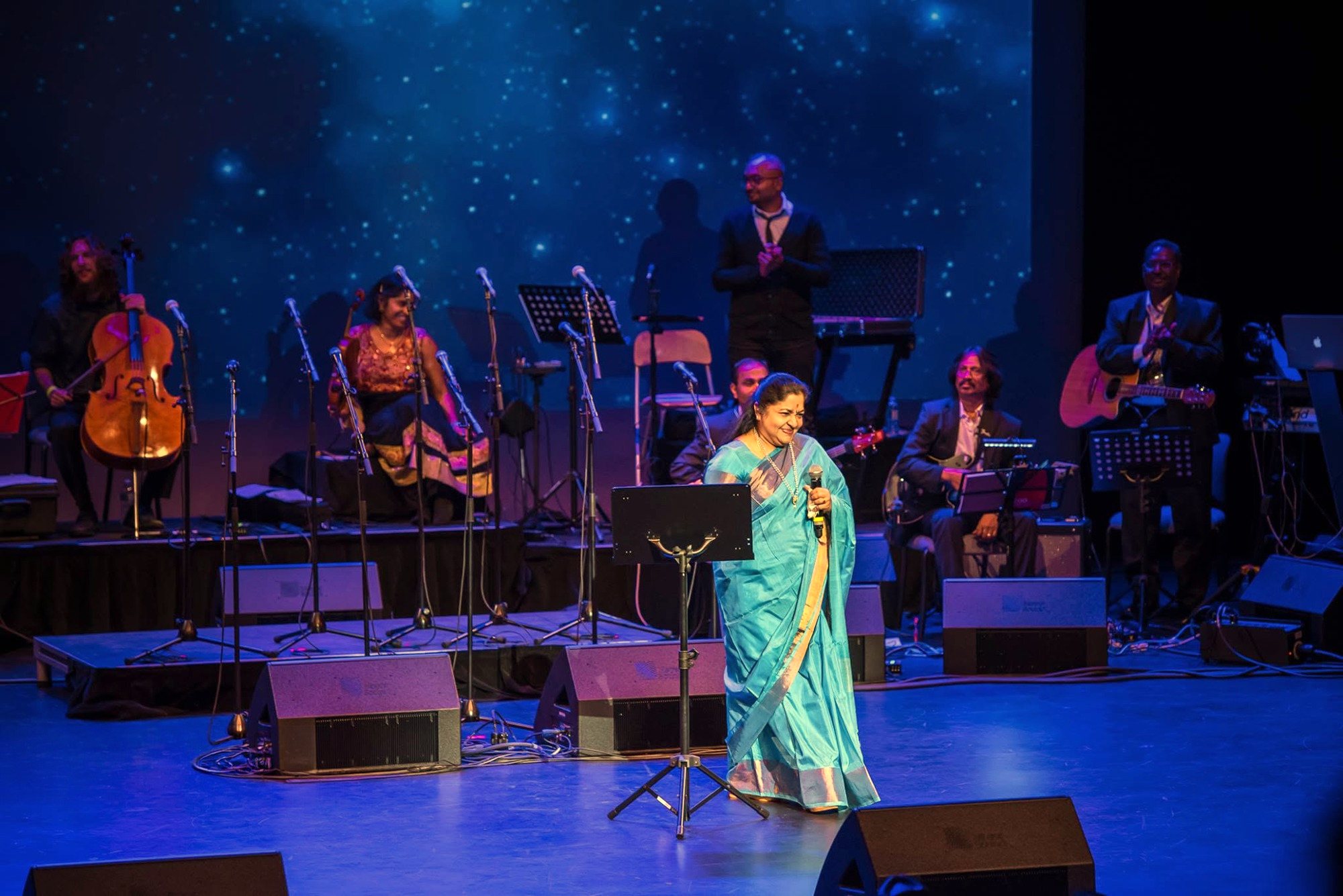 K. S. Chitra smiling on stage with the band behind her