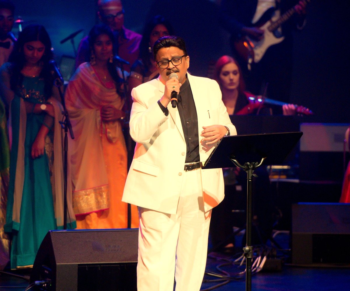 S. P. Balasubrahmanyam in a white suit singing at CineMusiq Euphoria, with the chorus behind him